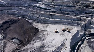 Extraction of hard coal. View from above. A large excavator loads soil with coal into a dump truck. Large coal mine.