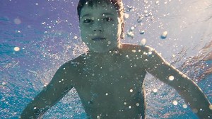 Boy dive in swimming pool, underwater slow motion