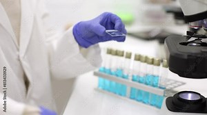 Lab worker pipetting drop on slide for microscopic analysis