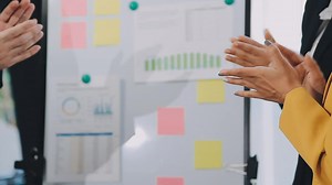 Download Two creative business people meeting and planning use post it notes sticky note on desk to share idea, Analysis data chart and graph with teamwork strategy brainstorming in office. for free