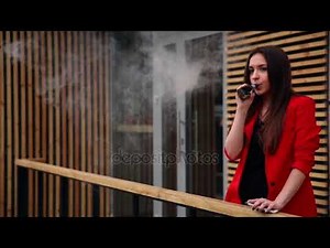Spectacular young brunette outside uses fashionable and healthy e-cigarette