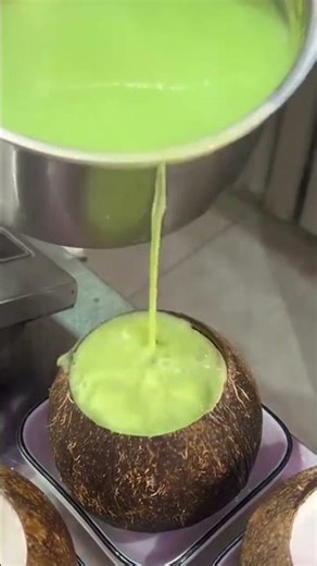 Pouring liquid pandan and arranging several toppings in a coconut shell container
