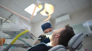 Dentist and patient in the medical center. The doctor makes a professional oral hygiene for the teeth of a mature man using dental tools. Deep teeth cleaning procedure by a dental hygienist