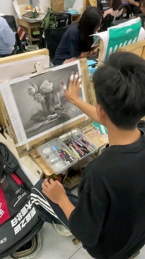 Charcoal Drawing Art Gallery on Instagram: "In this captivating still-life piece, the artist uses an innovative technique to achieve remarkable speed and precision. With multiple charcoal pencils taped to their fingers, each stroke brings out intricate details in the floral arrangement and surrounding objects. The balance of light and shadow adds depth, making the composition come to life with a touch of realism. This method is a testament to how creativity and technique merge, allowing for both