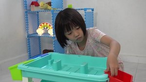 A cute Chinese little girl assemble the basket at the corner of plastic table