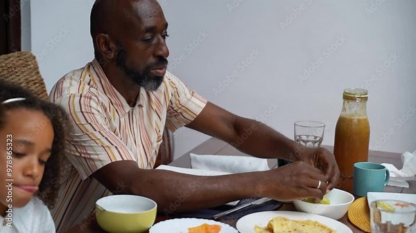 Happy diverse parents and children African-American Caucasian eating weekend lunch breakfast together. Family tradition, healthy food for children, leisure activity, care and relationships