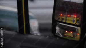 View of an ambulance with flashing lights as seen through a rear view mirror