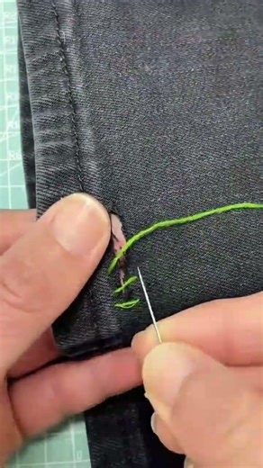 sewing a hole in denim fabric with bright green thread