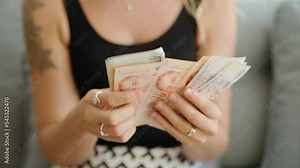 Young woman counting singapore dollars banknotes at home