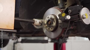 Auto mechanic refinishes brake disc with precision lathe. Vehicle servicing equipment in use for rotor resurfacing. Skilled tech operates car disc aligner in workshop. Automotive maintenance repair.