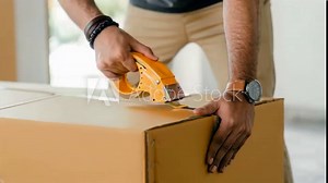Man sealing cardboard box with tape, closing box before moving or shipping