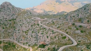 Cars, buses and motorcycles drive on European curved road in Majorca, Spain. Nus de Sa Corbata is a spectacular panoramic snake-like road with curves and rocky landscapes by the Mediterranean.