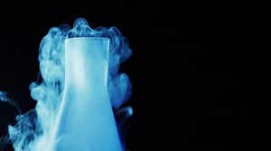 Cold blue flask with liquid nitrogen on black background. Concept of chemical experiments and tests. Edutainment. Copy space. 4k.
