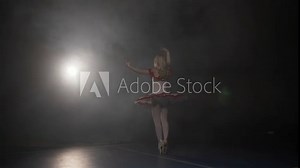 Ballerina dressed in white tutu and wearing pointe shoes dancing and rehearsing for the big show in a studio with smoke in slow motion