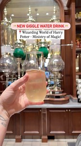 🚨You can order Giggle Water in The Wizarding World of Harry Potter - Ministry of Magic when Epic Universe opens May 22! . . 🙊 1 of my fav scenes from the @fantasticbeastsmovie ‘s is when Jacob Kowalski tries Giggle Water for the 1st time at The Blind Pig… So this was another musta-try for me during the media preview for Epic Universe this weekend . . 🥂 Giggle Water Amber shimmering elderflower prosecco spritz 💰$13 ✅ Mobile order available . . 📍In The WWoHP- Ministry of Magic: * Café L’air D