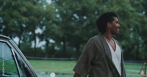 Young man standing out of his car in the countryside.