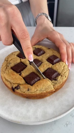Un cookie géant façon gâteau ? Je te vois déjà saliver derrière ton écran. 🍪🍌 Je te rassure, il est allégé et parfait pour ta collation. On se met aux fourneaux ? Ingrédients : - 100 g de banane bien mûre - 1 œuf - 70 g de farine d’avoine (flocons d’avoine mixés) - 1 cuillère à soupe de levure chimique - 80 g de yaourt de soja - 20 g de pépites de chocolat - Cannelle (à ton goût) - Environ 7 carrés de chocolat noir (min 70% de cacao) Instructions : 1. Préchauffe ton four à 180°C. 2. Prépare la
