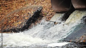 Environment protection concept. Industrial pipe discharging dirty waste. Runoff of excess water from the reservoir through metal pipes. Toxic waste in drain pipes.