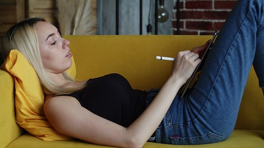 Woman drawing casually on a tablet on the couch - Free Stock Video