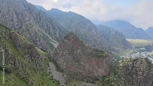 A dramatic view of a rocky mountain range with steep cliffs and rugged terrain. The sky is clear, highlighting the sharp features of the mountains and their natural beauty.