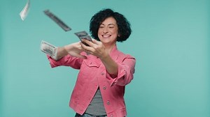 Money rain, falling dollars in slow motion. Successful business, finance economy footage concept shot 4K. Mature happy business woman scatter the dollars banknotes on isolated blue studio background