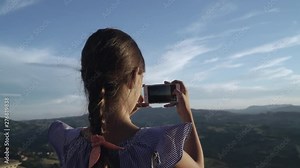 Little girl child take photos of mountains by smartphone camera at sunset. San Marino, Italy