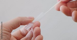 Swab placed inside a transparent tube and mixed with liquid, part of Covid-19 nasal rapid antigen self at home test procedure. Coronavirus, close up, hands.