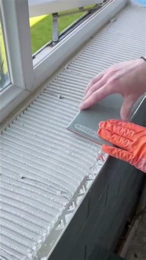 the process of installing tiles on the window frame wall