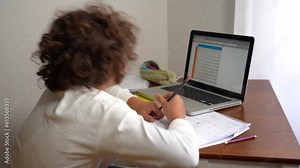 9-year-old elementary school boy doing homework - doing school-given math exercises for the summer holidays - childhood lifestyle student with computer laptop