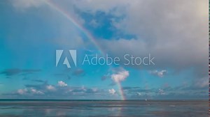 Double rainbows visible in sky above sea, after the dynamic movement of clouds. Time lapse.