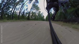 Rear wheel view of MTB bicycle. Chain drive, rear derailleur, cassette. Bicyclist rides mountain bike along sandy road in forest. Gearshift. Jockey wheels. Low angle view, wide lens, visual distortion