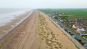 Discover the coastal haven of Mablethorpe through aerial views, spotlighting beach huts, sandy beaches, amusement parks, rides, and the tourist’s delight | Premium Stock Video Footage