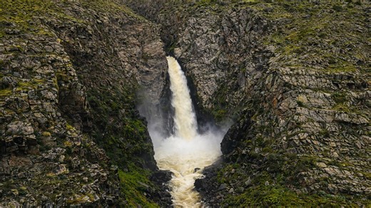 Powerful waterfall hidden between rugged mountain cliffs