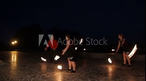 Men and women artists twist fiery circles on a fire show.Men and women artists does a fire performance.Fire show amazing at night.