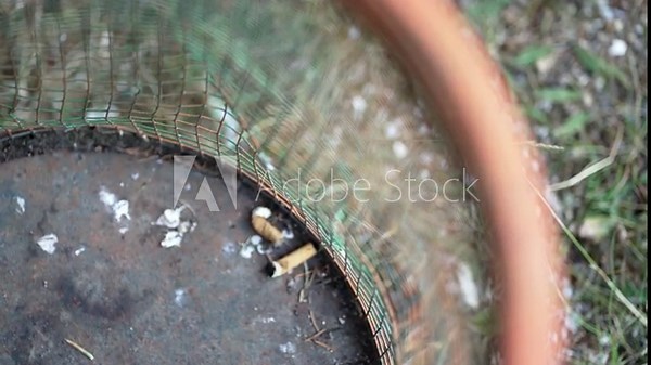 Ashtray garbage bin full with discarded cigarette stubs shows collective smoking habit