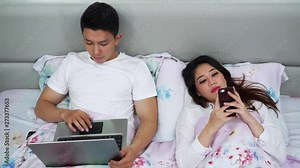 Young couple using a laptop computer and smartphone on the bed at home. Shot in 4k resolution