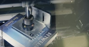 Automated Book Trimmer Machine Spins and Cuts Book Above. a close up above view of a machine spinning a paperback book to be trimmed on all sides