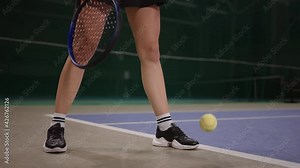 slender legs of professional female tennis player on court in start of match, lady is throwing ball on floor