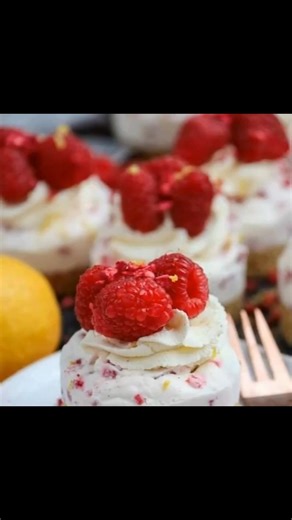 Mini Lemon & Raspberry Cheesecakes • 200 g digestives • 100 g unsalted butter (melted) • 300 g full-fat soft cream cheese/mascarpone (room temp) • 50 g icing sugar • 150 ml double cream • 1 tsp lemon extract or zest & juice of half a lemon • 200 g raspberries • 125 ml double cream (for decoration) • 1 tbsp icing sugar (for decoration) • lemon zest (for decoration) • 150 g raspberries (for decoration) • freeze dried raspberries (for decoration) For the Biscuit Bases: Blitz the biscuits in a food 