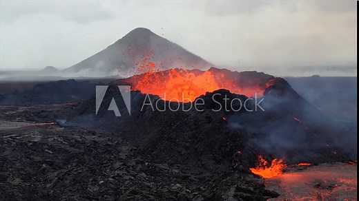 Super slow-motion footage of a volcano erupting in Iceland, capturing lava explosions from the crater and molten lava flowing across the dark volcanic terrain. Stock Video