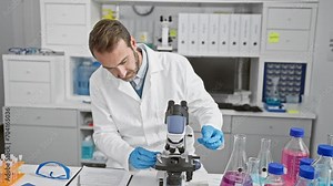 Bearded scientist man examines samples using microscope in a laboratory setting.