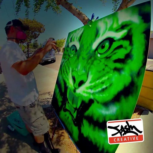 Graffiti muralist Fasm painting a green tiger with spray paint.