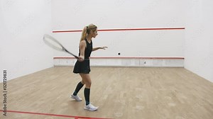 A young attractive woman playing squash on court, slow motion