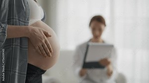 Pregnant woman consulting with a doctor. Close up tummy pregnant woman, patient answers gynecologist questions at hospital, medical clinic. Doctor examine pregnant belly check up. Pregnant check up.