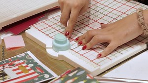 Using punch board and bone folder to cut paper for Christmas scrapbook