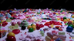 Multi-colored candy balls on icing sugar table. Candy sweets background made of assorted chocolate coated and jelly beans. Various shaped delicious sugary treats. Holiday festive background.