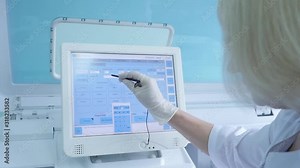 laboratory testing machine with test tubes in it and lab assistant setting data on the computer.