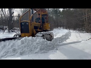 John Deere 450B plowing hard packed snow