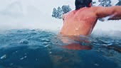 Winter swim. Young man swims in the winter lake. Splitted above and...