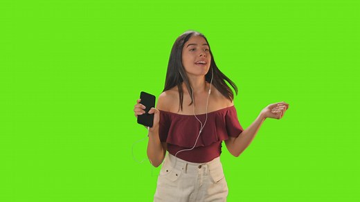 Girl dancing with her earphones on a green background - Free Stock Video